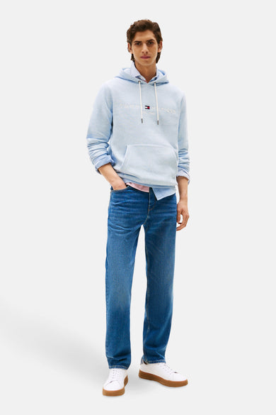 Blauwe sweater van TOMMY HILFIGER, gedragen over een overhemd met lange mouwen en een jeans.
