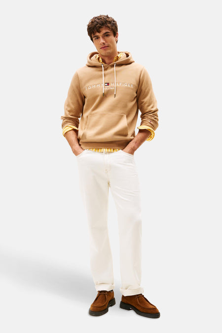 Beige sweater met capuchon van Tommy Hilfiger, met lange mouwen en witte broek en bruine schoenen.
