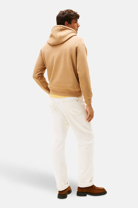 Beige sweater met ronde hals van TOMMY HILFIGER, met zichtbaar gestreept shirt eronder, gedragen met witte broek en bruine schoenen, achteraanzicht.
