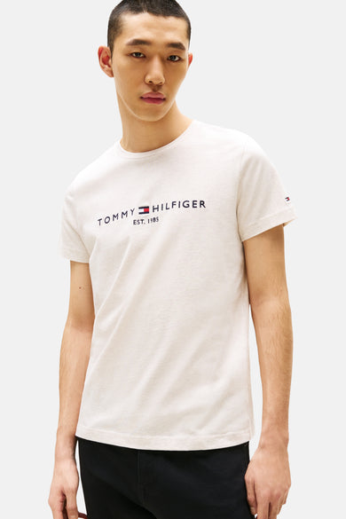 Beige T-shirt met korte mouwen van TOMMY HILFIGER, met logo op de borst en een effen achtergrond.
