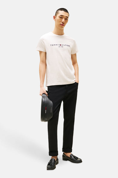 Beige T-shirt met korte mouwen van Tommy Hilfiger, gedragen met een zwarte broek en leren loafers.