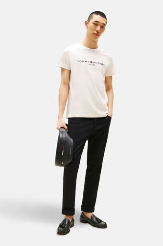 T-shirt beige à manches courtes de TOMMY HILFIGER, porté avec un pantalon noir et des loafers noirs, avec un sac.