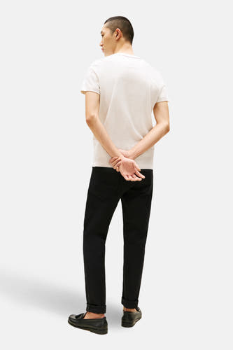 T-shirt beige à manches courtes de TOMMY HILFIGER, vu de dos, associé à un pantalon noir et des loafers.