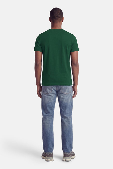 Groene korte mouwen T-shirt van TOMMY HILFIGER, achterzijde, gedragen met blauwe jeans en sneakers