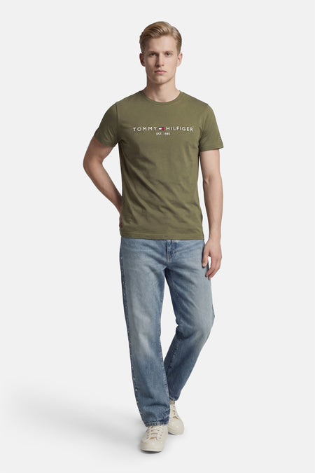 Groen T-shirt met korte mouwen van Tommy Hilfiger, gedragen met een blauwe jeans en witte sneakers.