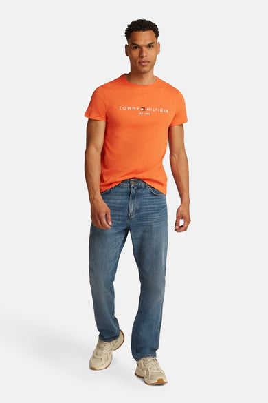 T-shirt à manches courtes orange de TOMMY HILFIGER, porté avec un jean bleu et des baskets couleur crème.