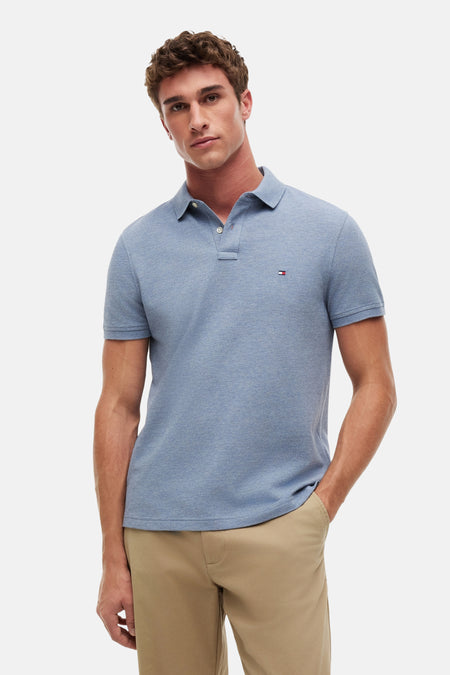 Blauwe polo van TOMMY HILFIGER met fijne piqué-structuur, witte knopen en een vlaglogo op de borst, gestyled met een khaki broek.