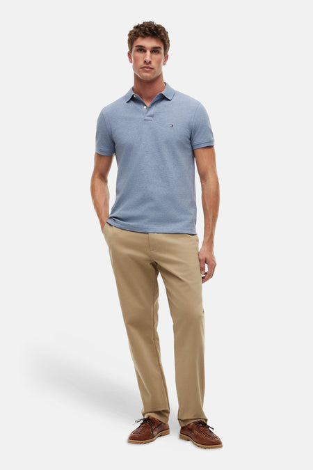 Blauw poloshirt van TOMMY HILFIGER met korte mouwen en knoopjes, gedragen met kaki broek en bruine schoenen.