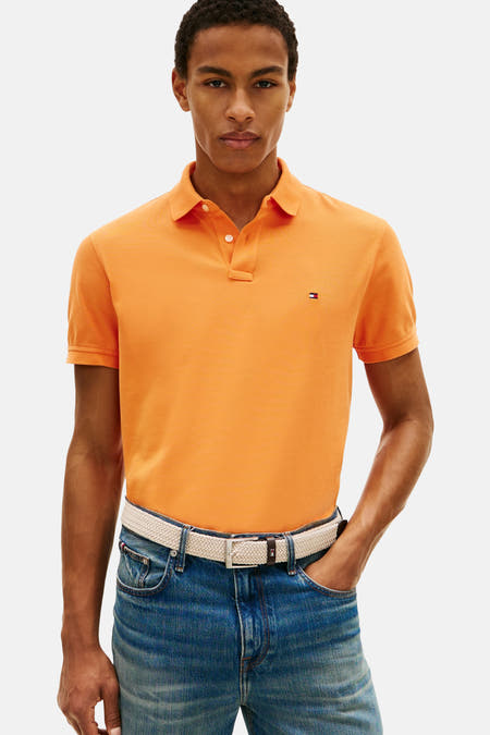 Oranje polo met korte mouwen van Tommy Hilfiger, gedragen met een gevlochten riem en jeans.
