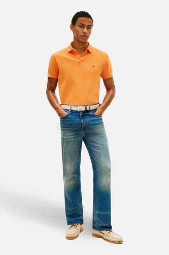 Oranje polo met korte mouwen van Tommy Hilfiger, met een klein logo op de borst, gedragen met jeans en boot schoenen.
