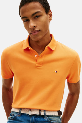 Oranje polo met korte mouwen van Tommy Hilfiger, met een geborduurde logo en gedragen met een jeans en riem.
