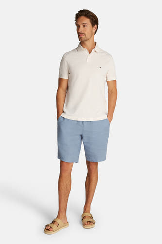 Ecru polo met korte mouwen van TOMMY HILFIGER, gedragen met blauwe shorts en sandalen.