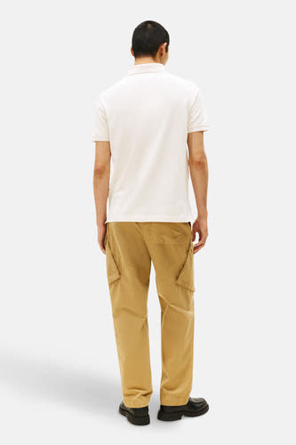 Ecru polo met korte mouwen van TOMMY HILFIGER, met kaki cargobroek en zwarte schoenen, van achteren gezien.