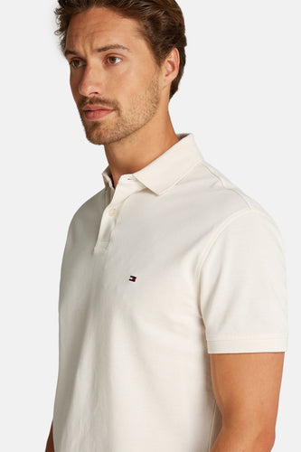 Man in gebroken witte polo met logo.