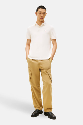 Man met polo, cargo broek en schoenen op witte achtergrond.