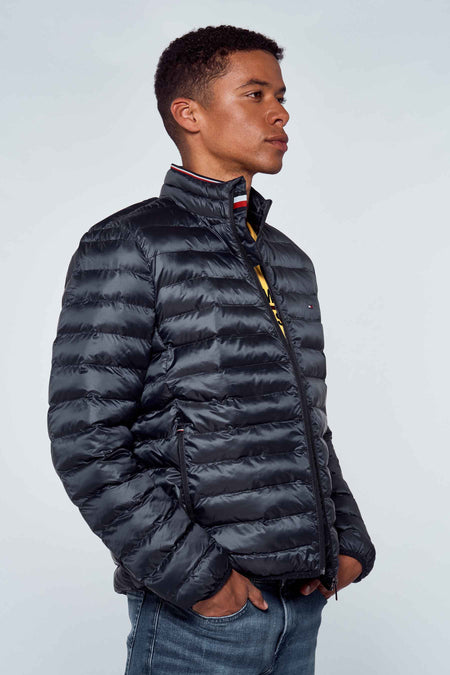 Veste de pluie bleue TOMMY JEANS, avec une texture pelucheuse et un col montant, portée sur un t-shirt jaune et des jeans bleus.