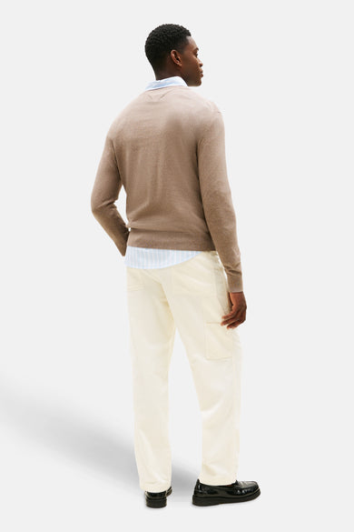 Gilet rond en beige TOMMY HILFIGER, avec un chemisier dessous, associé à une pantalon off-white et des chaussures noires, dos.