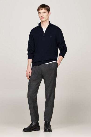 Blauwe coltrui van TOMMY HILFIGER, gedragen over een wit T-shirt, met grijze wollen broek en zwarte leren laarzen.