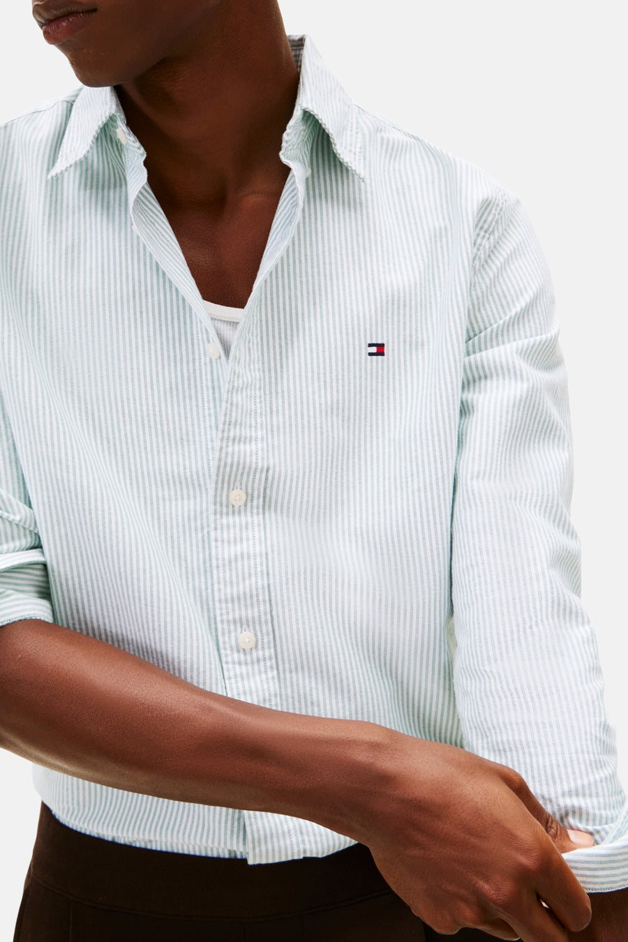 Groen gestreept overhemd met lange mouwen van TOMMY HILFIGER, gedeeltelijk opengeknoopt en gedragen over een wit hemd.