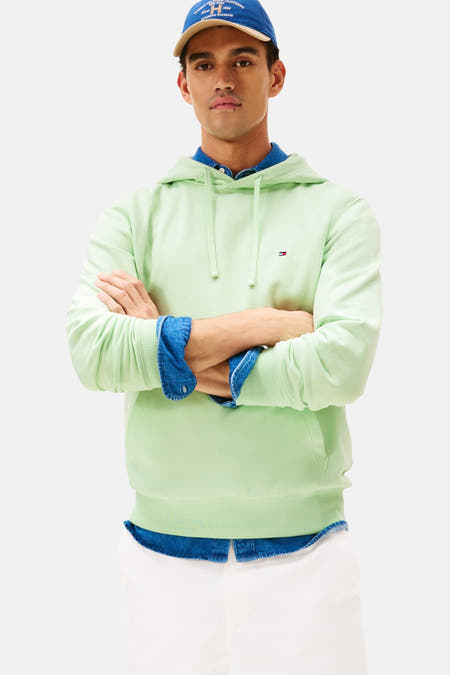 Groene sweater met kap van Tommy Hilfiger, gedragen met een spijkerblouse en een pet.