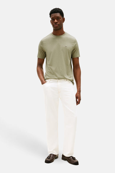 Groen T-shirt met korte mouwen van Tommy Hilfiger, met een logo op de borst, gecombineerd met een witte broek en bruine loafers.
