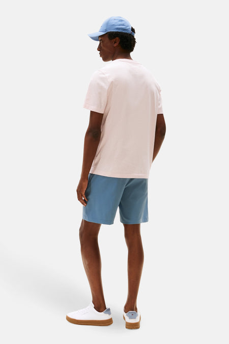 T-shirt rose à manches courtes de TOMMY HILFIGER, porté avec des shorts bleus et des baskets blanches.