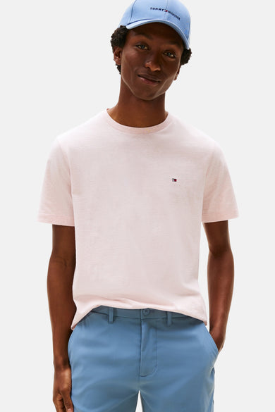 T-shirt rose à manches courtes de TOMMY HILFIGER, porté avec un pantalon bleu et un chapeau bleu.