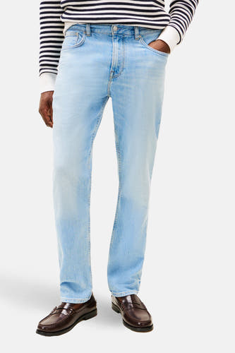 Jean en denim bleu clair droit de Tommy Hilfiger, combiné avec un pull rayé, une veste rouge et des mocassins marron.