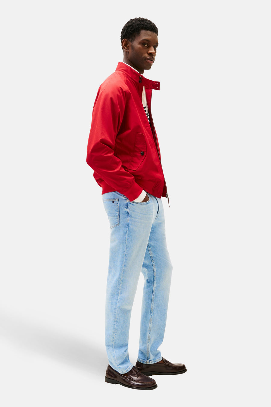 Jean en denim bleu clair droit de TOMMY HILFIGER, porté avec une veste rouge et des chaussures marron en vue de côté.