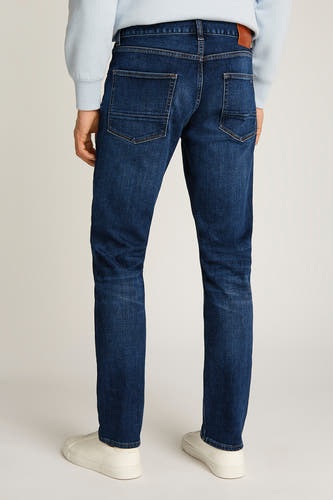 Jeans straight van donkerblauw denim van TOMMY HILFIGER, gezien van achteren, met beige sneakers en een lichtblauwe trui.
