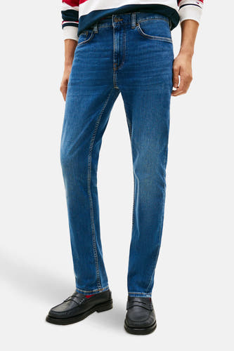 Slim fit jeans van mid blue denim van Tommy Hilfiger, gedragen met zwarte loafers.