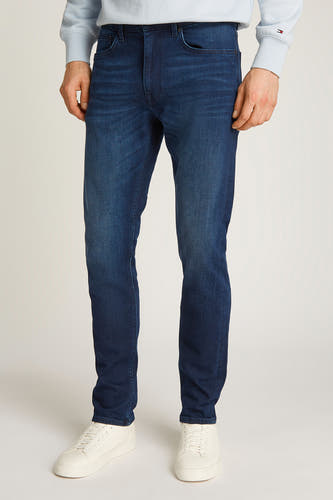 Rechte jeans van donkerblauw denim van Tommy Hilfiger, met lichte wassing en witte sneakers.
