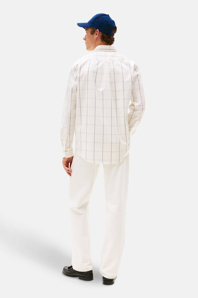 Beige overhemd met lange mouwen van TOMMY HILFIGER, met een zwart rasterpatroon, gecombineerd met witte broek en blauwe pet.