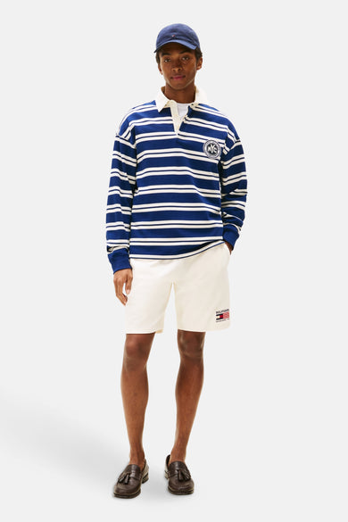 Pull-over bleu à longues manches de Tommy Hilfiger, avec des rayures blanches et un emblème sur la poitrine.