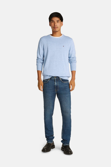 Lichtblauwe ronde hals trui van TOMMY HILFIGER, met klein logo op borst, gedragen met donkerblauwe jeans en zwarte schoenen, front view.
