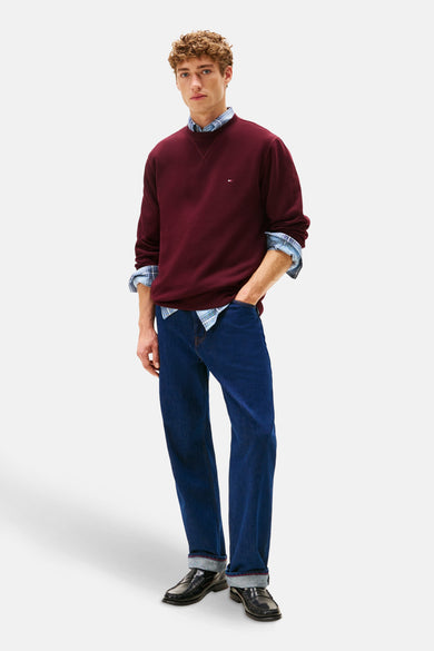 Rode sweater met ronde hals van TOMMY HILFIGER, gedragen over een geruit overhemd en gecombineerd met donkerblauwe jeans en zwarte loafers.
