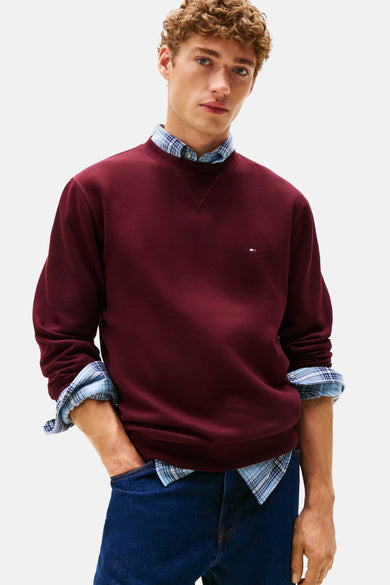 Rode sweater met ronde hals van TOMMY HILFIGER, gedragen over een geruit overhemd en met blauwe jeans.
