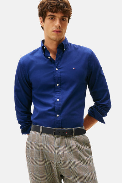 Blauw overhemd met lange mouwen van Tommy Hilfiger, gedragen met een geruite pantalon en riem.
