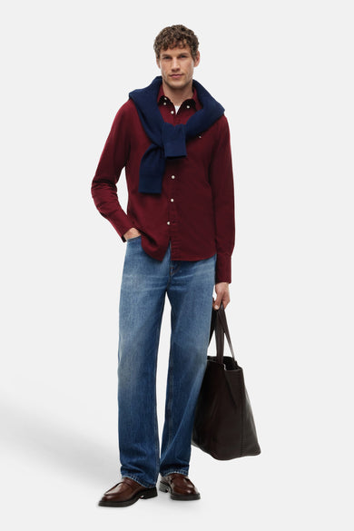 Chemise bordeaux à manches longues de TOMMY HILFIGER, portée avec un jean bleu et une écharpe bleu foncé, style de vie vue de face