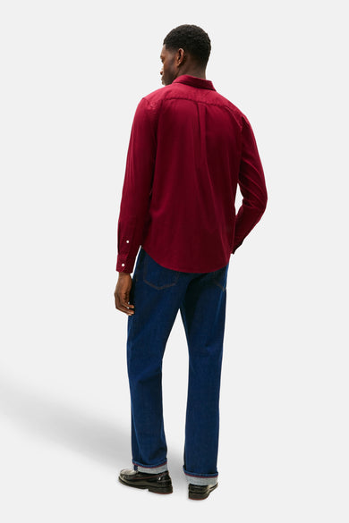 Bordeaux overhemd met lange mouwen van TOMMY HILFIGER, gezien van achteren, gecombineerd met donkerblauwe jeans en zwarte schoenen.