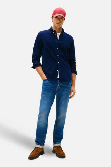 Chemise bleue de TOMMY HILFIGER, portée avec un T-shirt blanc, des jeans et des chaussures en cuir, avec une casquette rouge.