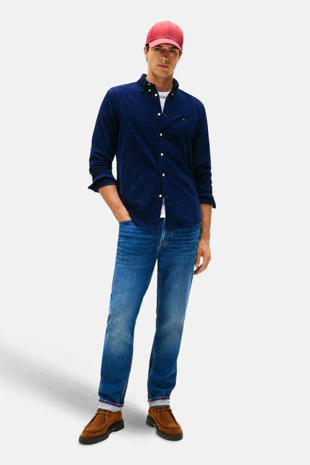 Blauw overhemd van TOMMY HILFIGER, gedragen met een wit T-shirt, jeans en suède schoenen, met een rode pet.