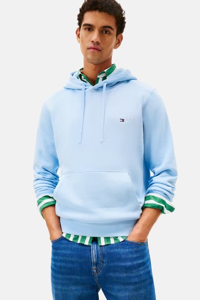 Blauwe sweater met kap van Tommy Hilfiger, met trekkoorden en buidelzak, gedragen over een gestreept overhemd, met jeans.
