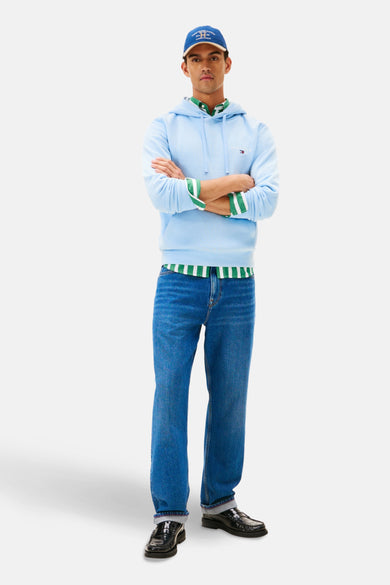 Blauwkleurige sweater met kap van Tommy Hilfiger, met lange mouwen, gecombineerd met een overhemd met groene strepen en jeans.