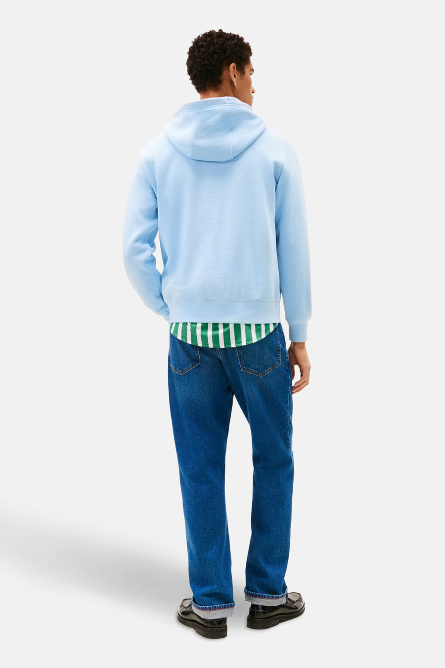 Blauwe sweater met kap van Tommy Hilfiger, met een gestreept shirt eronder en spijkerbroek.