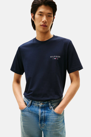 T-shirt bleu à manches courtes de TOMMY HILFIGER, vu de dos, associé à des jeans et des chaussures noires.