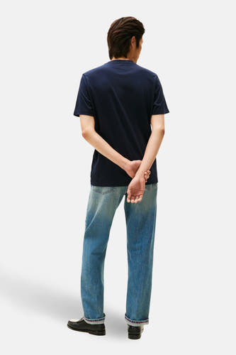 Blauw T-shirt met korte mouwen van TOMMY HILFIGER, gezien van achteren, gecombineerd met jeans en zwarte schoenen.
