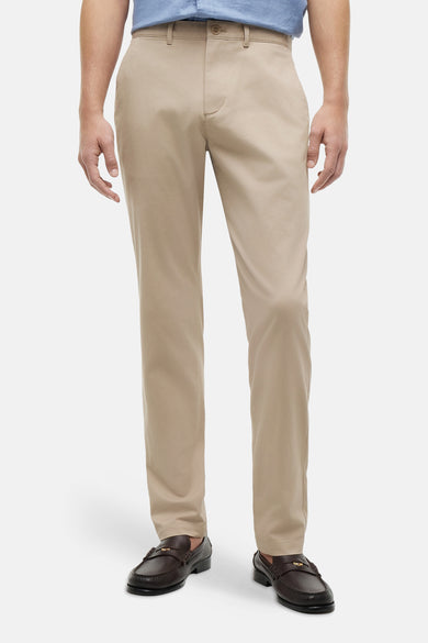 Chino beige de TOMMY HILFIGER, porté par un homme avec une chemise bleue, une ceinture marron et des mocassins foncés.