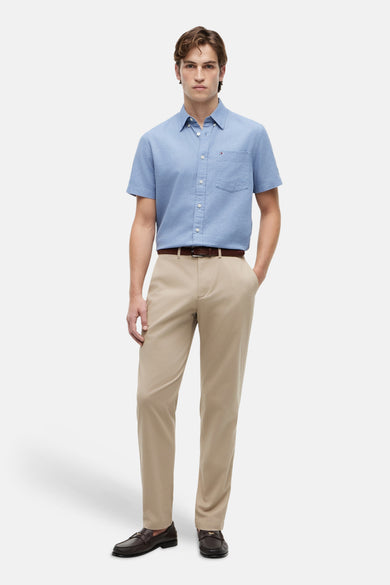 Beige chino van TOMMY HILFIGER, gedragen door een man met een blauw overhemd, bruine riem en donkere mocassins.