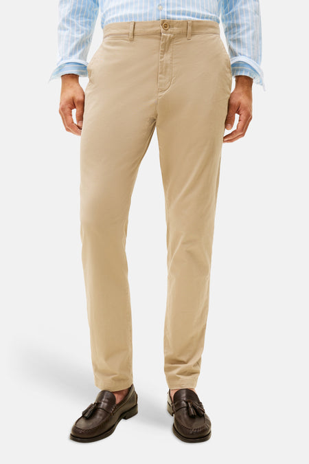Chino beige de TOMMY HILFIGER, porté avec une chemise rayée bleu clair et des mocassins à pampilles marron.